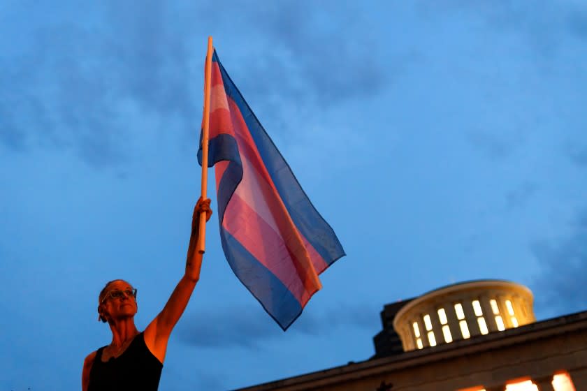 COLUMBUS, UNITED STATES - 2021/06/24: Cole Ramsey, 39, of South Linden holds a Transgender Pride Flag in front of the Ohio Statehouse to protest the passing of legislation against Trans Women playing sports in high school and college. Transgender rights advocates stood outside of the Ohio Statehouse to oppose and bring attention to an amendment to a bill that would ban transgender women from participating in high school and college women sports. The original bill that this transgender ban was added to dealt with compensation for college students to profit off of their name, image and likeness. The addition of transgender ban to this bill was a surprise, because a transgender ban bill already is in existence. (Photo by Stephen Zenner/SOPA Images/LightRocket via Getty Images)