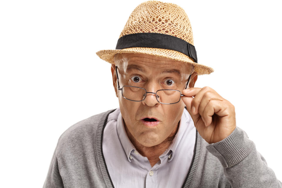 Older man with surprised expression adjusting glasses