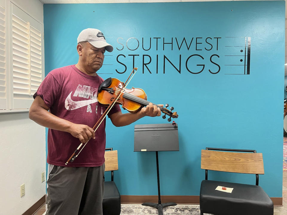 A Pascua Yaqui tribe member plays a violin at a Tucson, Ariz. music store on April, 2023.(Raymond V. Buelna via AP)