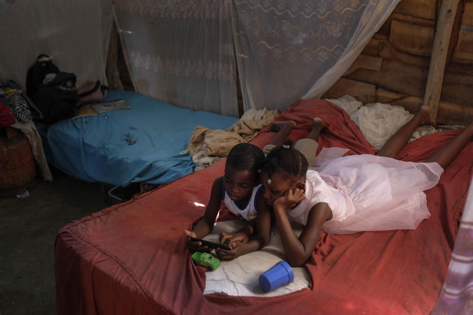 Rosemita Dorerus' children play with a cell phone in their home in the La Punta community of Santo Domingo, Dominican Republic, Sunday, Nov. 21, 2021. Dorerus was nine months pregnant when she was detained in early November inside a hospital in the capital of Santo Domingo. She was later deported, leaving behind three young children. “Every day they ask me, ‘When is Mom coming home? When is Mom coming home?’” said her partner, Guens Molière. “They cry almost daily.” (AP Photo/Matias Delacroix)