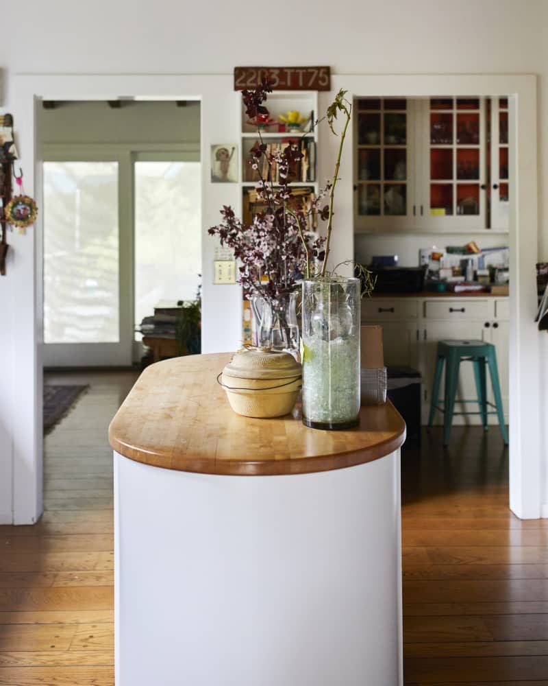 A kitchen island topped with plants and pottery.