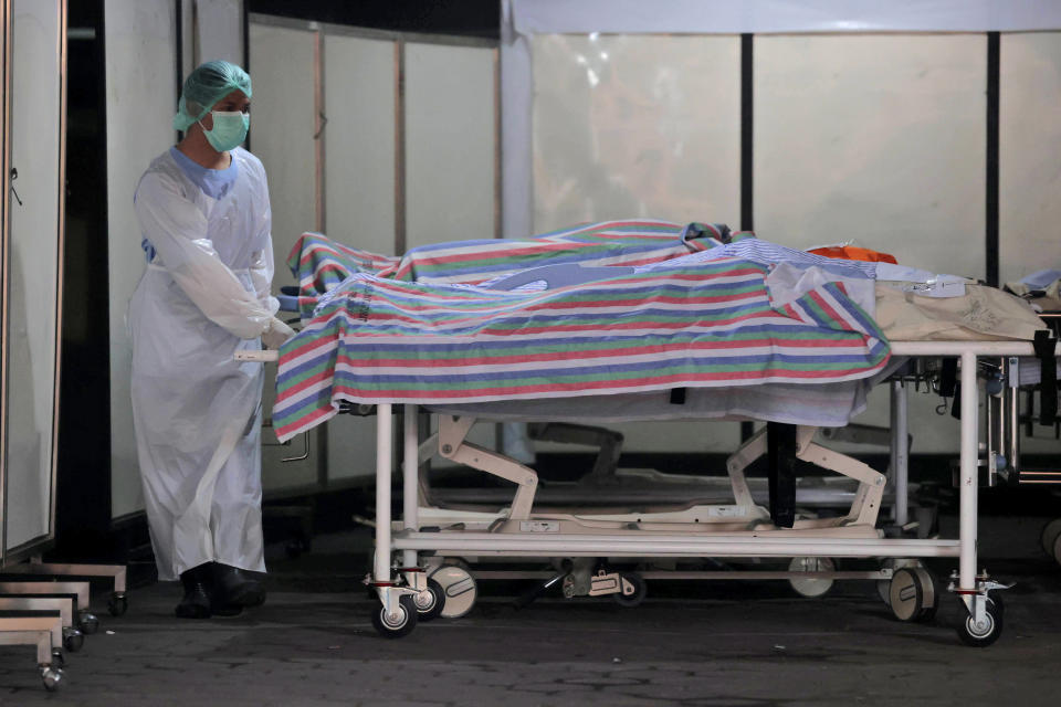 A medical worker arranges gurneys carrying the bodies of the victims of a soccer match stampede at the Saiful Anwar Hospital in Malang, East Java, Indonesia, Sunday, Oct. 2, 2022. Panic at an Indonesian soccer match after police fired tear gas to to disperse supporters invading the pitch left over 100 people dead, mostly trampled to death, police said Sunday. (AP Photo/Trisnadi)