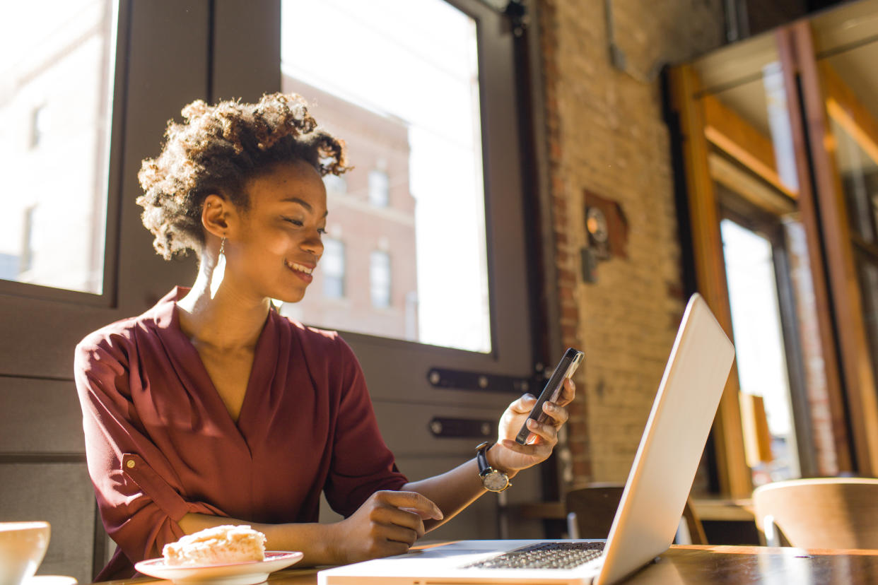 Young businesswoman sitting in cafe, using laptop and smartphone