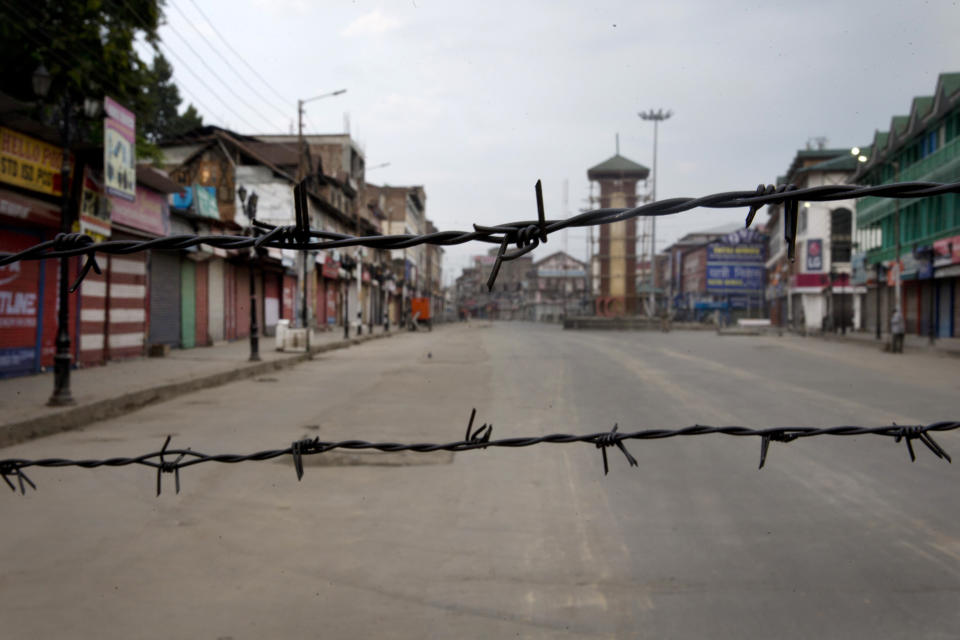 FILE- In this Aug. 6, 2019 file photo, a deserted street is seen through a barbwire set up as blockade during curfew in Srinagar, Indian controlled Kashmir. The beautiful Himalayan valley is flooded with soldiers and roadblocks of razor wire. Phone lines are cut, internet connections switched off, politicians arrested. Narendra Modi, the prime minister of the world’s largest democracy has clamped down on Kashmir to near-totalitarian levels. (AP Photo/Dar Yasin)