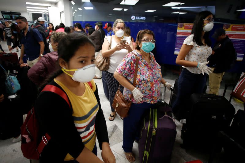 Stranded Ecuadorian tourists, wearing face masks, are pictured while waiting for a new flight after Ecuador's government closed its borders due to the spread of the coronavirus disease (COVID-19), at the Benito Juarez International Airport in Mexico City