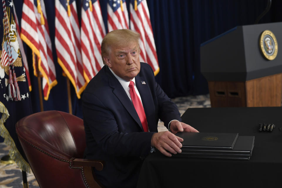 President Donald Trump prepares to sign four executive orders during a news conference at the Trump National Golf Club in Bedminster, N.J., Saturday, Aug. 8, 2020. Seizing the power of his podium and his pen, Trump on Saturday moved to bypass the nation's elected lawmakers as he claimed the authority to defer payroll taxes and extend an expired unemployment benefit after negotiations with Congress on a new coronavirus rescue package collapsed.(AP Photo/Susan Walsh)