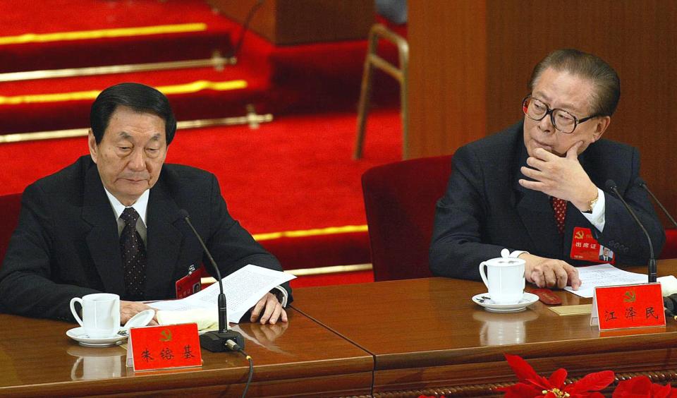 Premier Zhu Rongji (L) reads a copy of the resolution as President Jiang Zemin looks over at the closing session of the 16th Communist Party Congress, 14 November 2002, at the Great Hall of the People in Beijing.  China began a sweeping generational change of its leadership today as President Jiang and five other elderly leaders stood down from their posts in the ruling Communist Party.  AFP PHOTO/Frederic J. BROWN (Photo by Frederic J. BROWN / AFP) (Photo by FREDERIC J. BROWN/AFP via Getty Images)