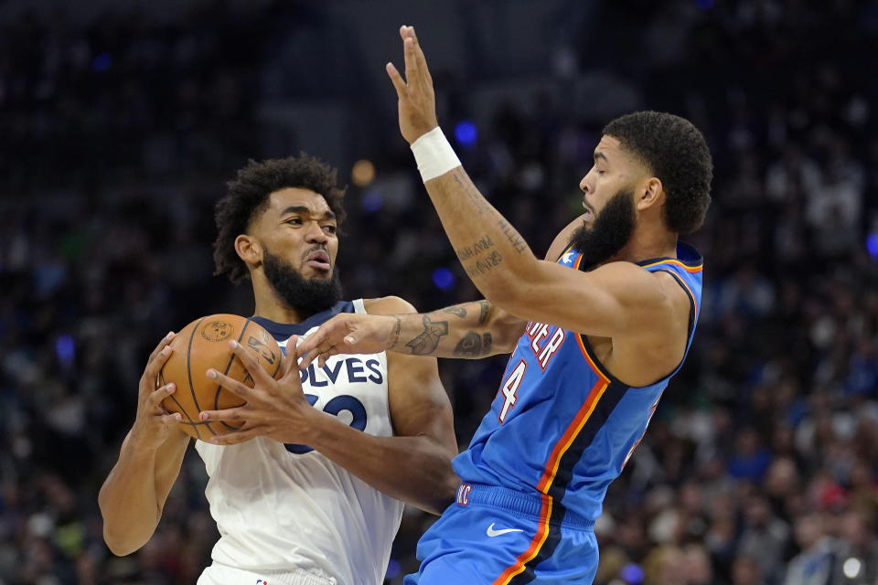 Minnesota Timberwolves center Karl-Anthony Towns (32) works toward the basket against Oklahoma City Thunder forward Kenrich Williams (34) during the first half of an NBA basketball game Wednesday, Oct. 19, 2022, in Minneapolis. (AP Photo/Abbie Parr)