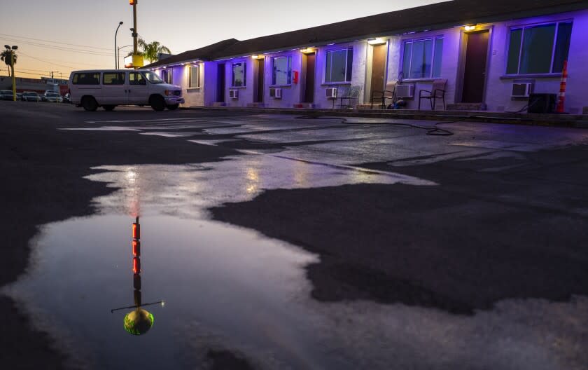 The neon sign for the Desert Moon Motel is reflected in the water in the parking lot