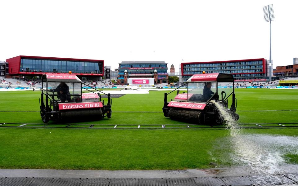 Ground staff attempt to clear the water off the field during day two of the First Rothesay Test match at the Emirates Old Trafford, Manchester