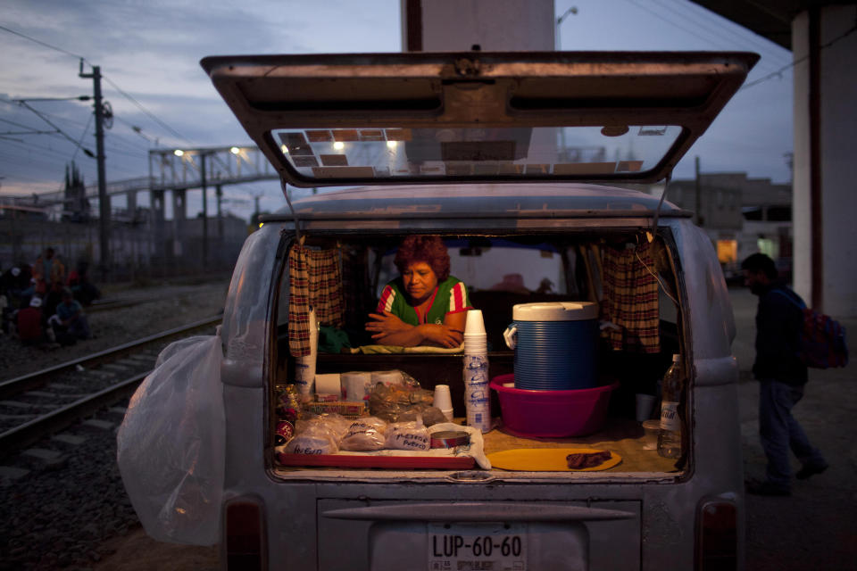 In this May 17, 2012 photo, Maria Campos, waits for customers to sell them food from her car, parked near the train tracks where migrants, mostly from Honduras, wait for trains going north, in Lecheria on the outskirts of Mexico City. While the number of Mexicans heading to the U.S. has dropped dramatically, a surge of Central American migrants is making the 1,000-mile northbound journey this year, fueled in large part by the rising violence brought by the spread of Mexican drug cartels. (AP Photo/Alexandre Meneghini)