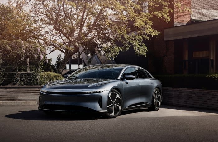 A Lucid Air sedan parked in front of a Hamptons summer house. 