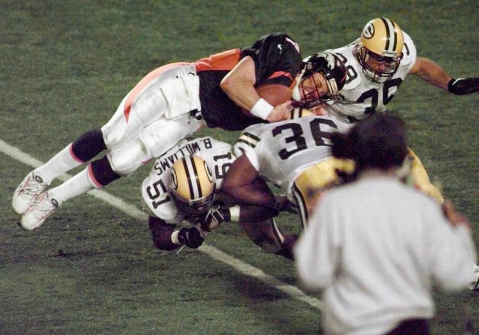 The Helicopter -- aged Denver quarterback John Elway, diving for a first-down at the end of a 6-yard gain, is about to be sent spinning by Green Bay’s Brian Williams (51) and Elroy Butler (36) during Super Bowl XXXII.