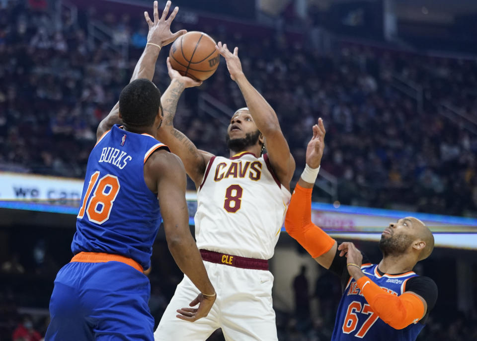 Cleveland Cavaliers' Lamar Stevens (8) shoots between New York Knicks' Alec Burks (18) and Taj Gibson (67) in the first half of an NBA basketball game, Monday, Jan. 24, 2022, in Cleveland. (AP Photo/Tony Dejak)