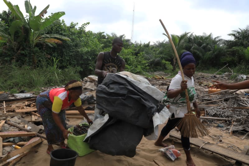 Displaced inhabitants of the Okun glass community pick up their belongings amidst the rubble at the site of demolition in Lagos