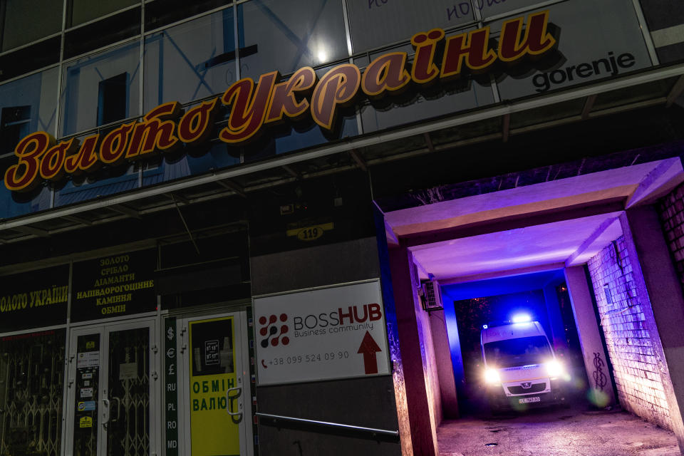 In this photo taken on Thursday, May 7, 2020, an ambulance carrying a patient with coronavirus leaves the yard of an apartment building with a jewelry shop "Gold of Ukraine", top, in Chernivtsi, Ukraine. Ukraine's underfunded health care system was quickly overwhelmed by the coronavirus, with medics accounting for one fifth of all coronavirus cases in the country.(AP Photo/Evgeniy Maloletka)