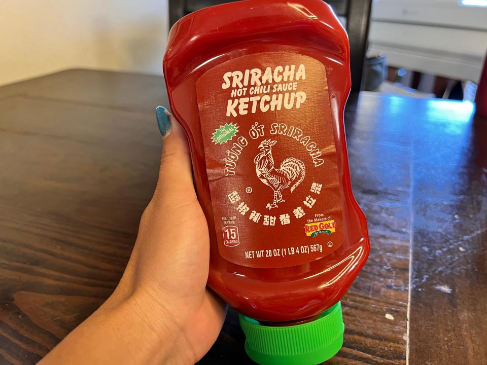 Hand holding a bottle of Sriracha ketchup