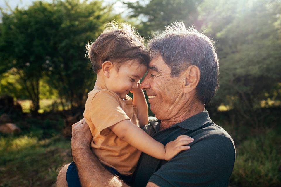 A grandpa cuddles his young grandson.