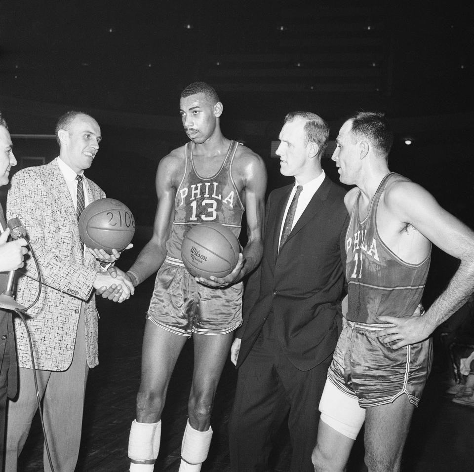 Neil Johnston (in dark suit), coach of the Philadelphia Warriors, watches as George Yardley of the Syracuse Nationals congratulates Wilt Chamberlain of the Warriors after the Chamberlain set a new single-season scoring record on Feb. 10, 1960. Yardley was first to crack the 2,000 barrier. At right is Warrior Paul Arizin, who broke Yardley's record.