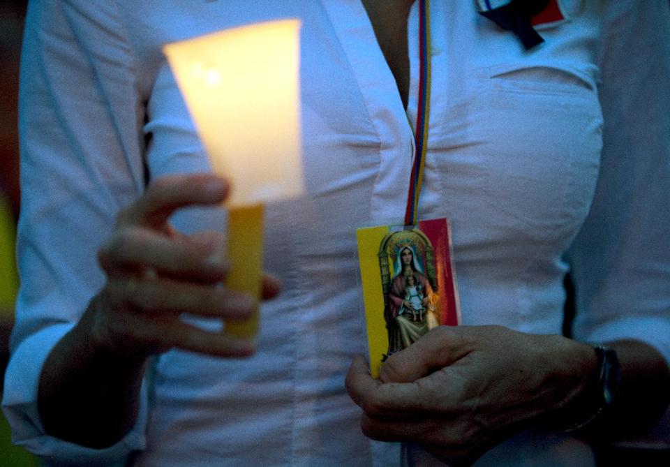 A demonstrator holds candle and a image of the Virgin Mary during a protest against the violence, in Caracas, Venezuela, Friday, March 7, 2014. Venezuela is coming under increasing international scrutiny amid violence that most recently killed a National Guardsman and a civilian. United Nations human rights experts demanded answers Thursday from Venezuela's government about the use of violence and imprisonment in a crackdown on widespread demonstrations. (AP Photo/Fernando Llano)