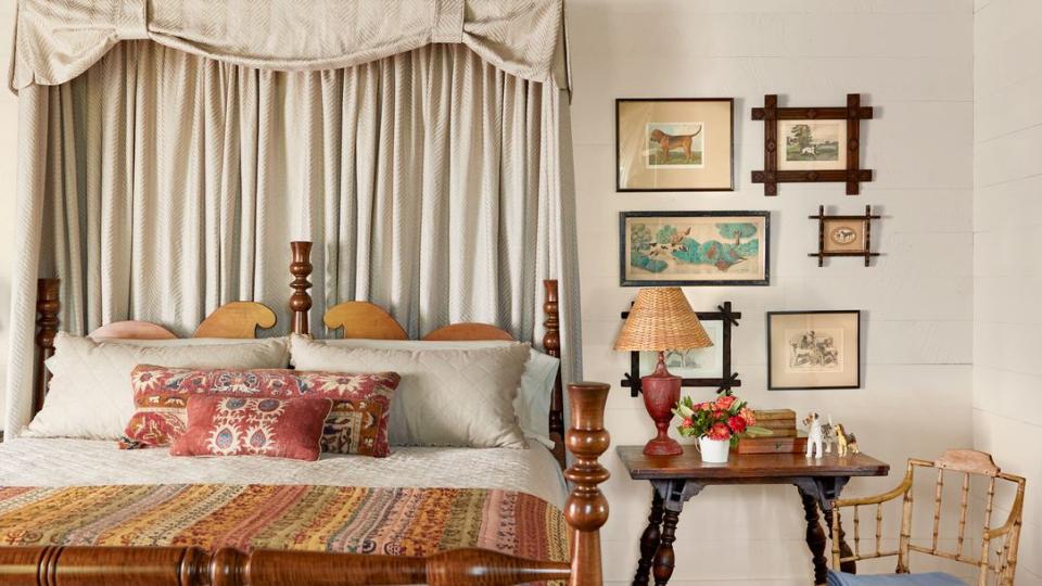 a bedroom with a wood frame bed and a vintage rug and a collection of dog paintings on the wall