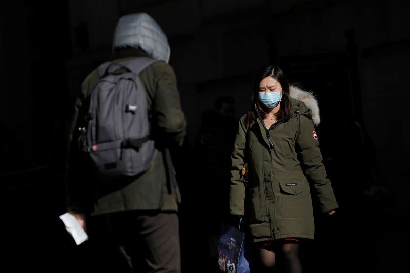 A woman in a face mask walks in the downtown area of Manhattan, New York City, after further cases of coronavirus were confirmed in New York