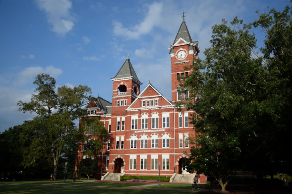 William J. Samford Hall, a four-story red brick building topped with a clock tower and a smaller tower. White-trimmed windows dot the exterior.