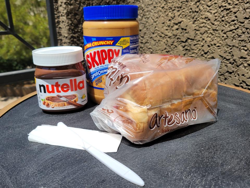 Nutella, Skippy peanut butter, a loaf of bread, and a plastic knife.