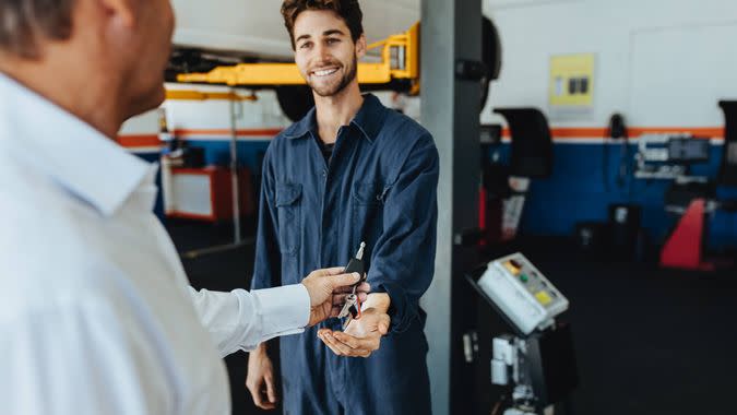 Mechanic receiving car keys from customer in automobile service center.