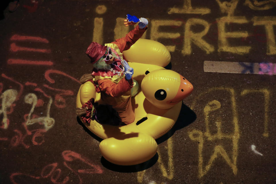 A clown carries a large inflatable duck at a pro-democracy rally in Bangkok, Thailand, Wednesday, Nov. 18, 2020. Police in Thailand's capital braced for possible trouble Wednesday, a day after a protest outside Parliament by pro-democracy demonstrators was marred by violence that left dozens of people injured. (AP Photo/Sakchai Lalit)