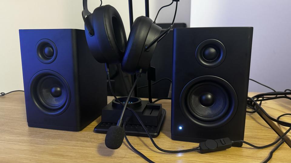 The NZXT Relay speakers, headphones and standing on a wooden table