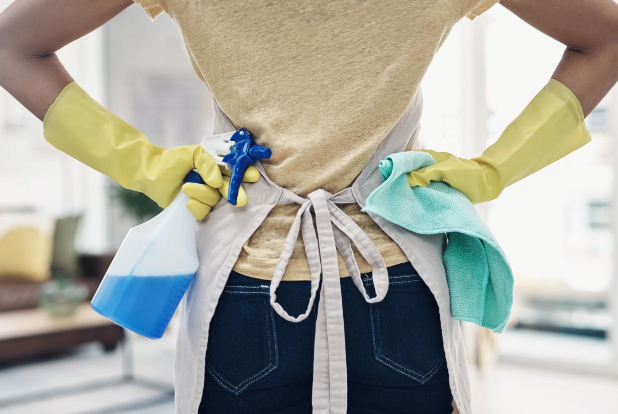 Shot of an unrecognisable woman using rubber gloves and disinfectant to clean her home