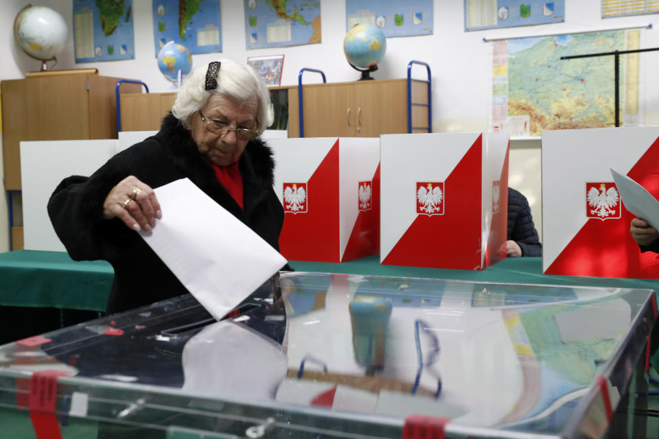 A voter casts her ballot at a polling station in Warsaw, Poland, Sunday, Oct. 13, 2019. Poles are voting Sunday in a parliamentary election, that the ruling party of Jaroslaw Kaczynski is favored to win easily, buoyed by the popularity of its social conservatism and generous social spending policies that have reduced poverty. (AP Photo/Darko Bandic)