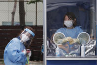 A medical worker holds a portable fan during the sweltering heat while police officers are tested for COVID-19 at a makeshift clinic at the Seoul Metropolitan Police Agency in Seoul, South Korea, Wednesday, Aug. 19, 2020. (AP Photo/Ahn Young-joon)