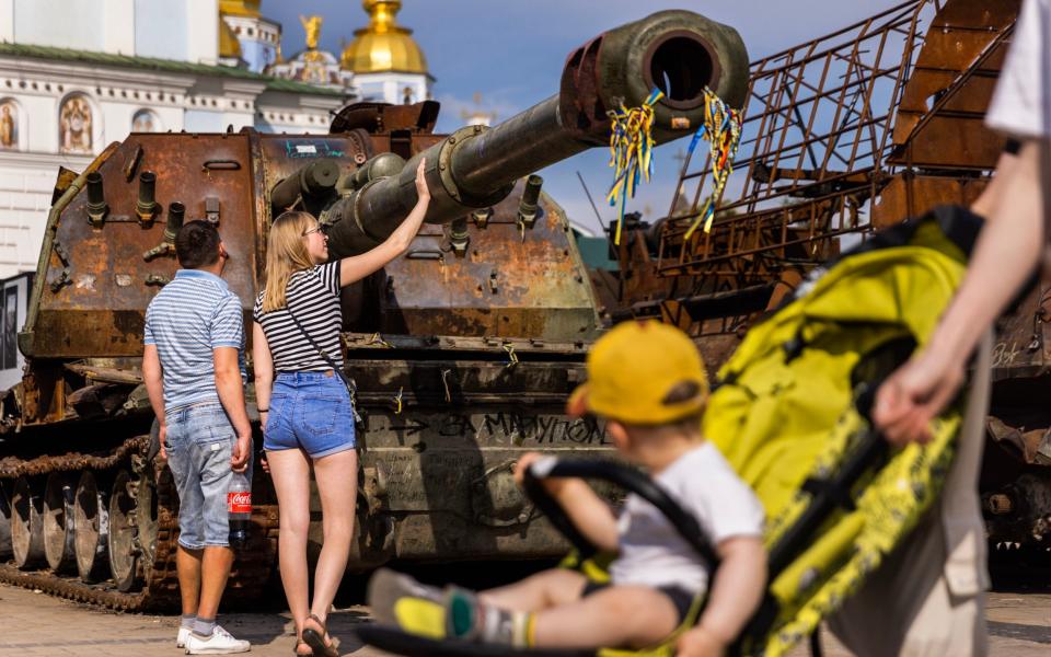 A woman touches the barrel of a destroyed Russian tracked vehicle displayed on Saint Michael's Square in Kyiv - Daniel Carde /Avalon
