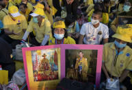 Supporters of Thai monarch display images of the late King Bhumibol Adulyadej ahead of the arrival of King Maha Vajiralongkorn and Queen Suthida to participate in a candle lighting ceremony to mark birth anniversary of late King Bhumibol Adulyadej at Sanam Luang ceremonial ground in Bangkok, Thailand, Saturday, Dec. 5, 2020. (AP Photo/Gemunu Amarasinghe)