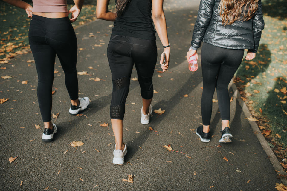 Three women wearing leggings walking down a pathway