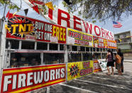 FILE - In this July 2, 2013, file photo, a family purchases fireworks at a TNT Fireworks stand in the City of Monterey Park, Calif. With fewer professional celebrations on July 4, 2020, due to the coronavirus pandemic, many Americans are bound to shoot off fireworks in backyards and at block parties. And they already are: Sales have been booming. (AP Photo/Nick Ut, File)