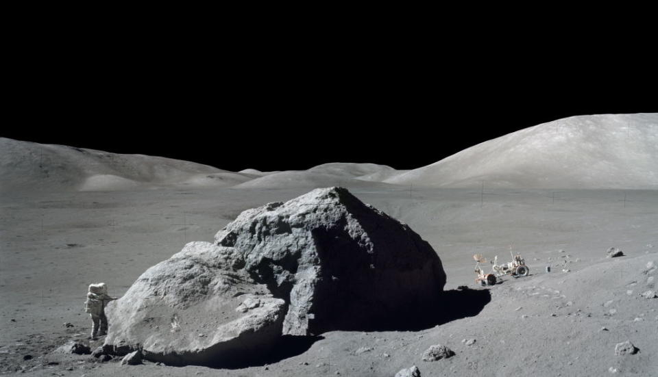 He's walking next to a very large rock with black expanse behind him