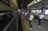 Police trainees stand spaced apart outside a train during a simulation exercise for proper social distancing at the LRT-2 station on Tuesday, May 26, 2020, in Manila, Philippines. The exercise is held to prepare for the possible resumption of public transportation as the community lockdown to prevent the spread of the new coronavirus might be more relaxed next week. (AP Photo/Aaron Favila)