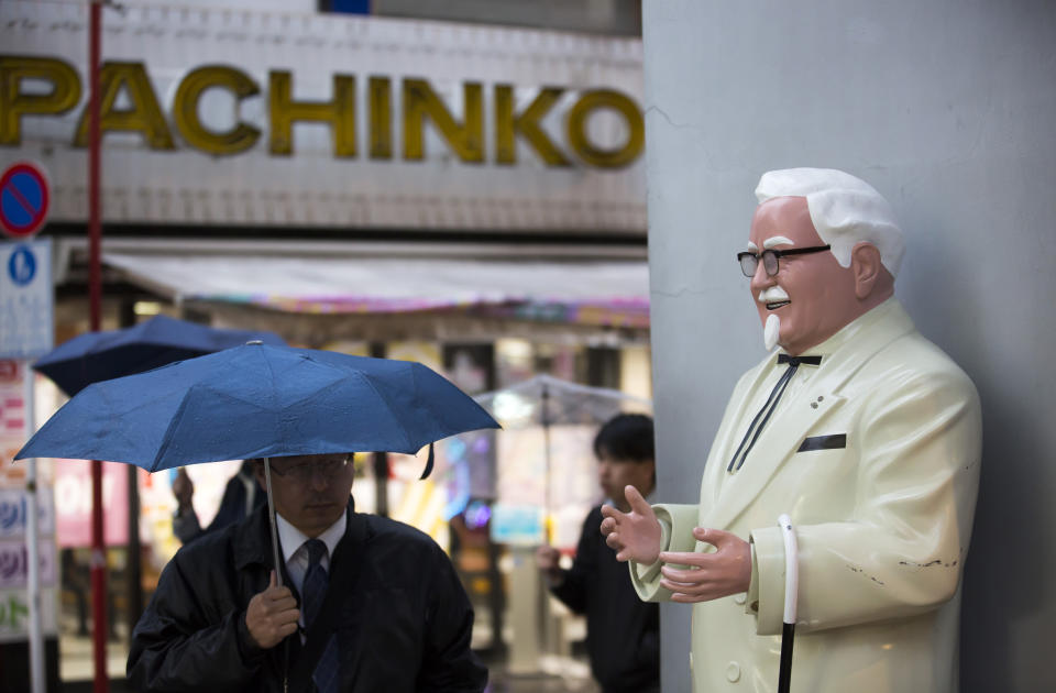 A pedestrian holding an umbrella walks near a statue of Colonel Harland Sanders, the founder of Kentucky Fried Chicken (KFC), outside a Kentucky Fried Chicken Japan Ltd. restaurant in the Akihabara district of Tokyo, Japan, on Thursday, Feb. 9, 2017. (Photo: Tomohiro Ohsumi/Bloomberg)