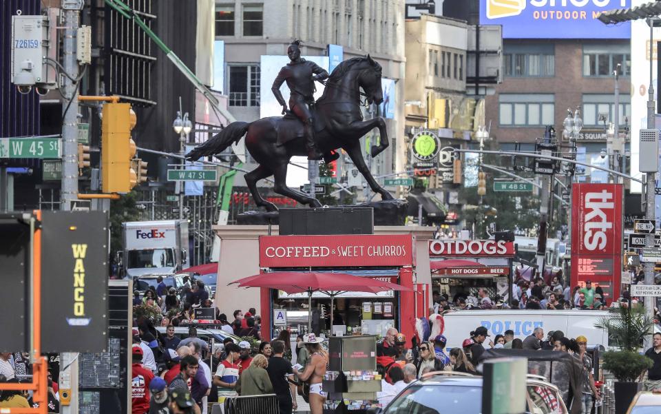 A bronze sculpture, "Rumors of War," by artist Kehinde Wiley, appears in Times Square at an unveiling on Friday Sept. 27, 2019, in New York. The work, depicting of a young African American in urban streetwear sitting astride a galloping horse, will be exhibited through December 1. (AP Photo/Bebeto Matthews)