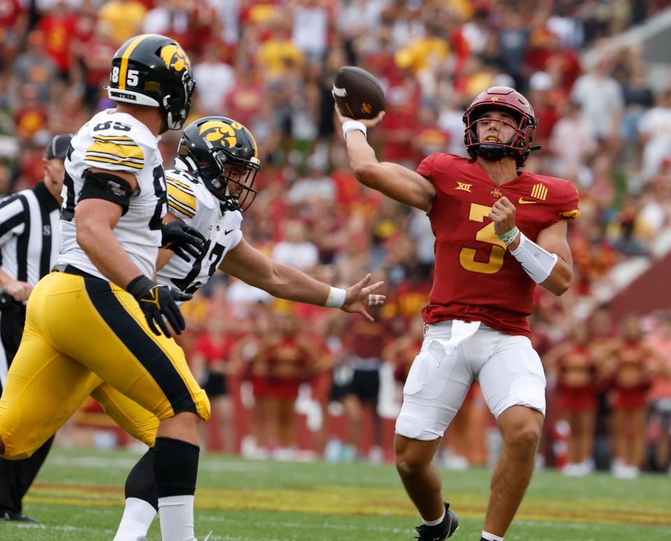Iowa State QB Rocco Becht throws under pressure from Iowa defensive lineman Logan Lee (#85) and defensive end Joe Evans (#13). Becht tossed a TD and a pick-6 on Saturday in a 20-13 loss to the Hawkeyes.
