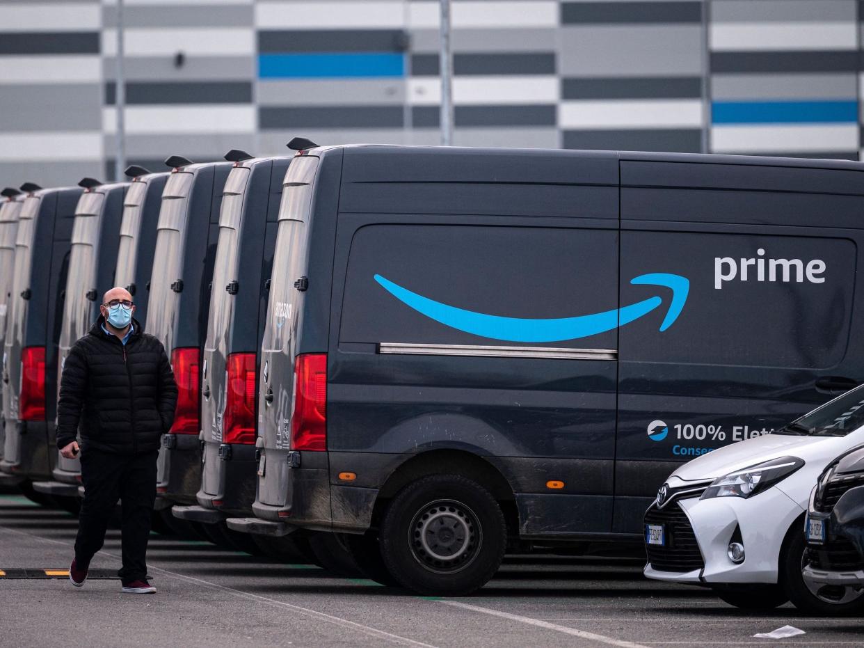 An Amazon employee walks by an Amazon Prime delivery truck in the company's premises in Brandizzo, near Turin, March 22, 2021