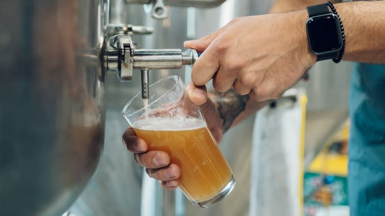 Hands pouring a pint of beer at a brewery