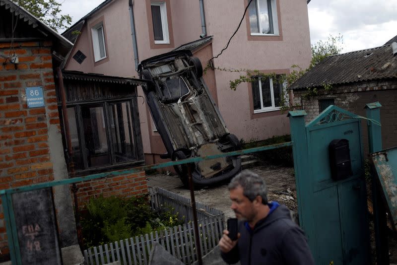 Un hombre pasa junto a un automóvil volcado después de que un bombardeo ruso golpeara un garaje, en medio del ataque de Rusia a Ucrania, en Járkov, Ucrania