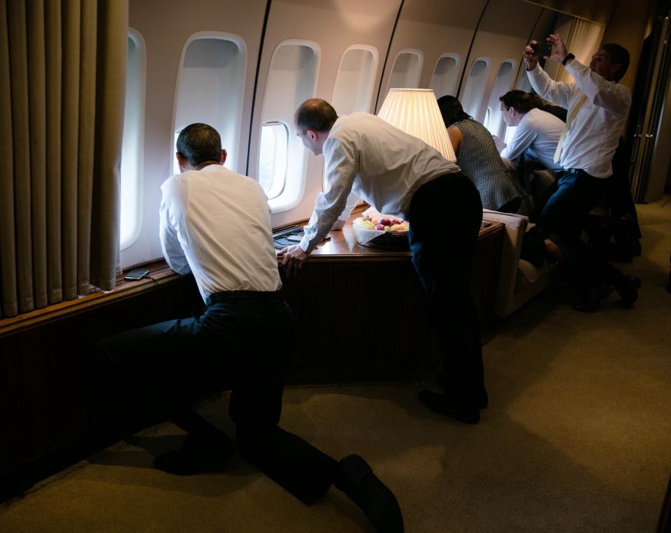 President Barack Obama joins others in looking out the window of Air Force One on the final approach into Havana.