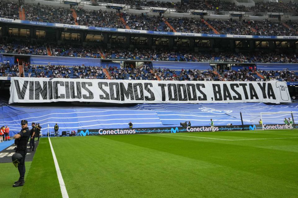 Spectators sit behind a banner reading 'We're all Vinicius" prior to a Spanish La Liga soccer match between Real Madrid and Rayo Vallecano at the Santiago Bernabeu stadium in Madrid, Spain, Wednesday, May 24, 2023. (AP Photo/Manu Fernandez)