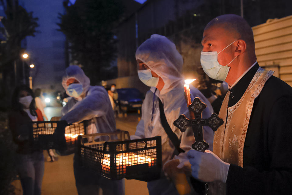 A priest distributes holy light to households during the coronavirus pandemic in Bucharest, Romania, Saturday, April 18, 2020. Priests accompanied by volunteers distributed the holy light ahead of the usual time, at midnight, as people observed the interdiction to join religious celebrations in the week leading to the Orthodox Easter, imposed across Romania as authorities try to limit the spread of the COVID-19 infections. (AP Photo/Vadim Ghirda)