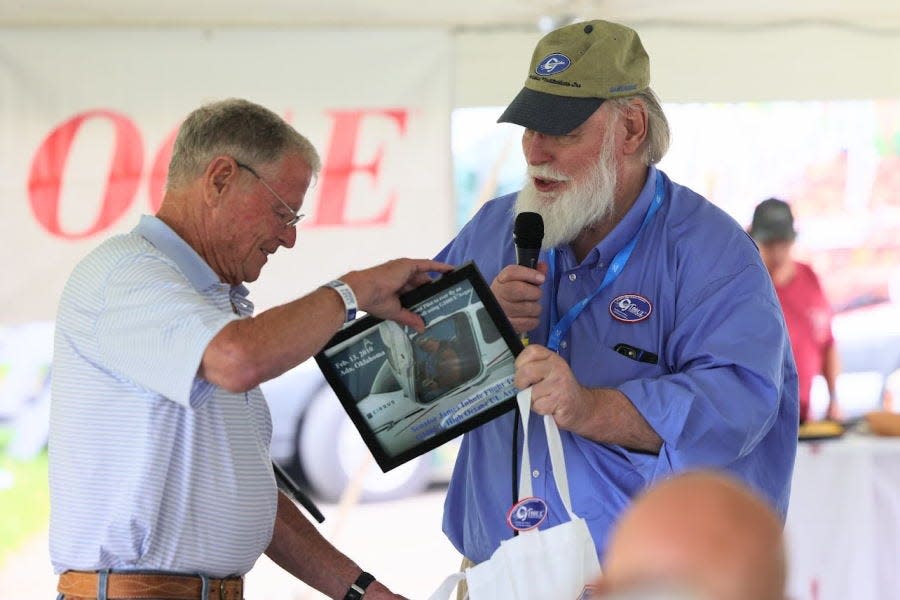 At EAA AirVenture in 2021, George Braly gives Senator James Inhofe (R-Ok.) an 11-year-old photograph taken when Inhofe became the second pilot (after Braly) to ever pilot an aircraft operating on G100UL.